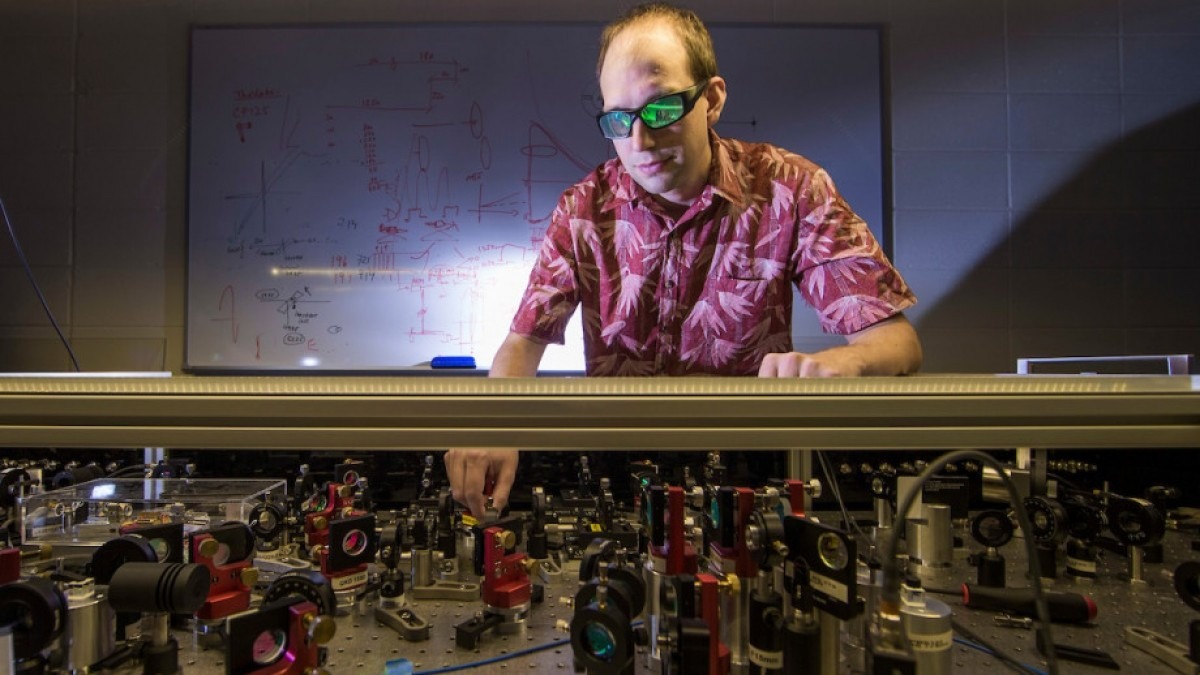 Francis Bennet is in the laboratory with sunglasses on as he tests laser optics equipment.