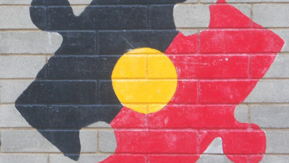 Aboriginal flag in shape of jigsaw piece, mural on wall.