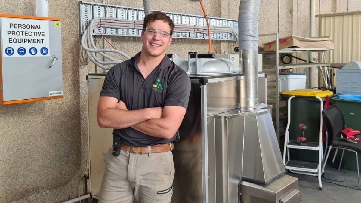 Ryan Pike stands in front of industrial-looking lab equipment, smiling at the camera.