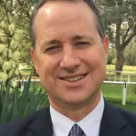 A smiling man wearing a suit