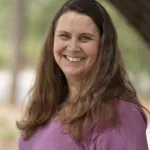 A smiling woman in a purple shirt