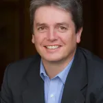 A man in a suit smiling