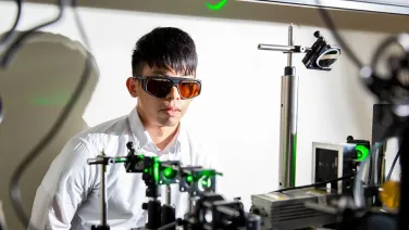 Man with safety goggles and a lab coat with laser equipment