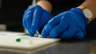 Gloved hands cutting up a pill