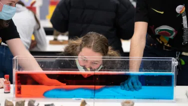 Woman looking at science experiment with red and blue liquid.