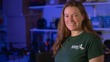 A woman in a green t-shirt in a lab smiling