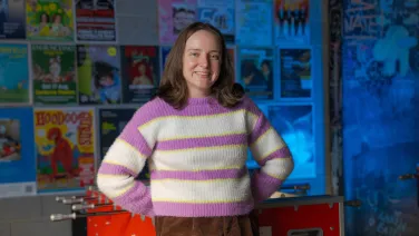A smiling woman leaning against a football table game
