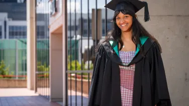 Woman in graduation gown and hat smiling