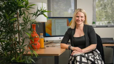 A smiling woman sitting at a desk in an office