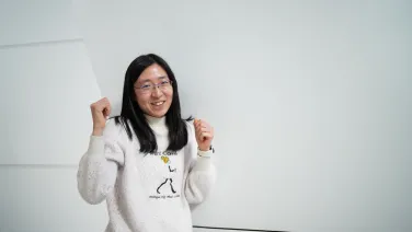 Sasanan Trakansuebkul with her arms in the air celebrating her 3 minute thesis win.