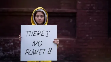 Child holding sign that says 'there's no planet B'
