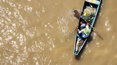 Man in a fishing boat on brown water