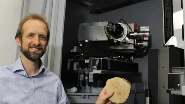 Man hold piece of wood in front of Micro CT equipment