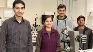Four Future Research Talent scholars standing behind a microscope