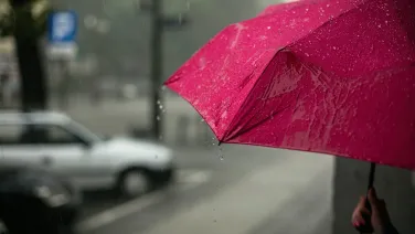 Someone holding a red umbrella in the rain