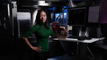 A scientist stands in a lab, holding a fossil.