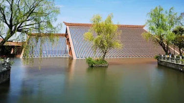 A flooded house, from outside. Only the roof is visible above the water.