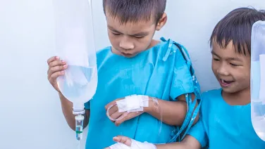 Two boys holding medical fluid bags